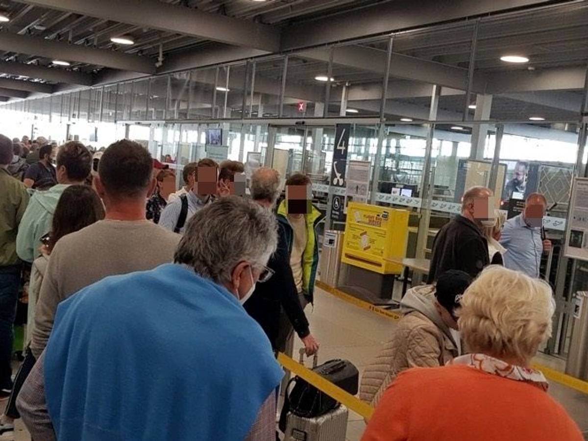 Menschen warten in einer langen Schlange vor der Sicherheitskontrolle im Flughafen Köln/Bonn.