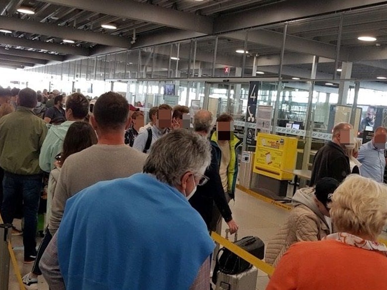 Menschen warten in einer langen Schlange vor der Sicherheitskontrolle im Flughafen Köln/Bonn.