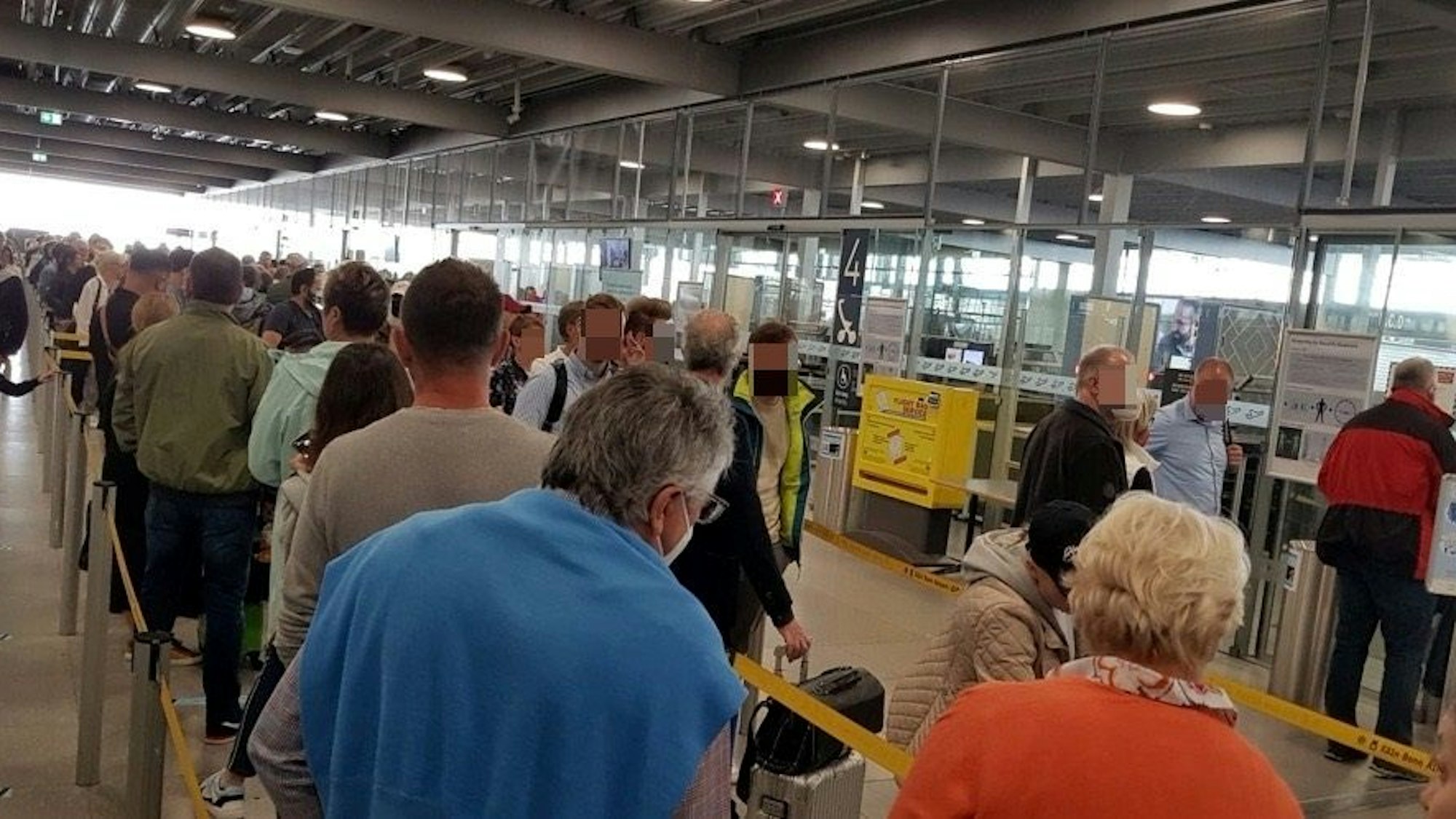 Menschen warten in einer langen Schlange vor der Sicherheitskontrolle im Flughafen Köln/Bonn.