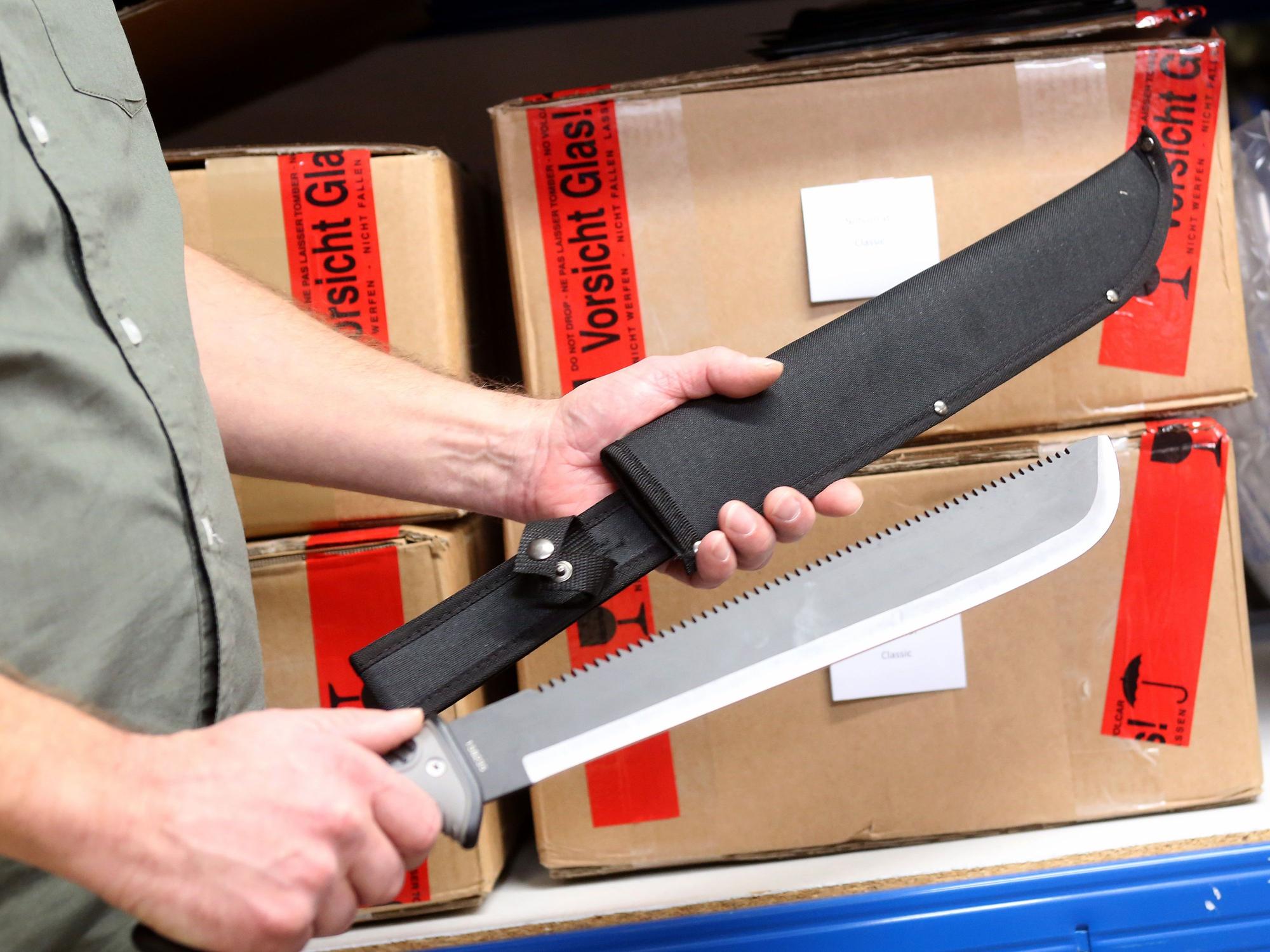 Stephan B. aus Kleve, Prepper und Internethändler, führt in seinem Versandkeller eine Machete vor.