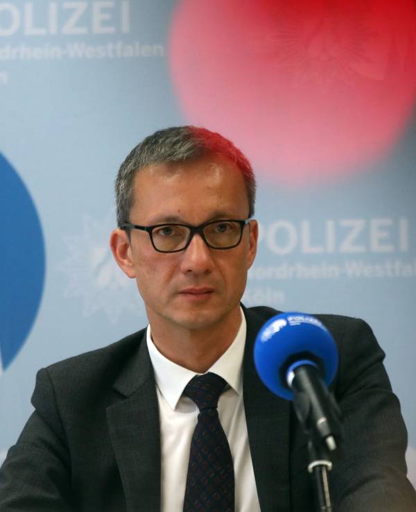 Der Kölner Polizeipräsident Falk Schnabel sitzt auf einem Podium vor einem Mikrofon.