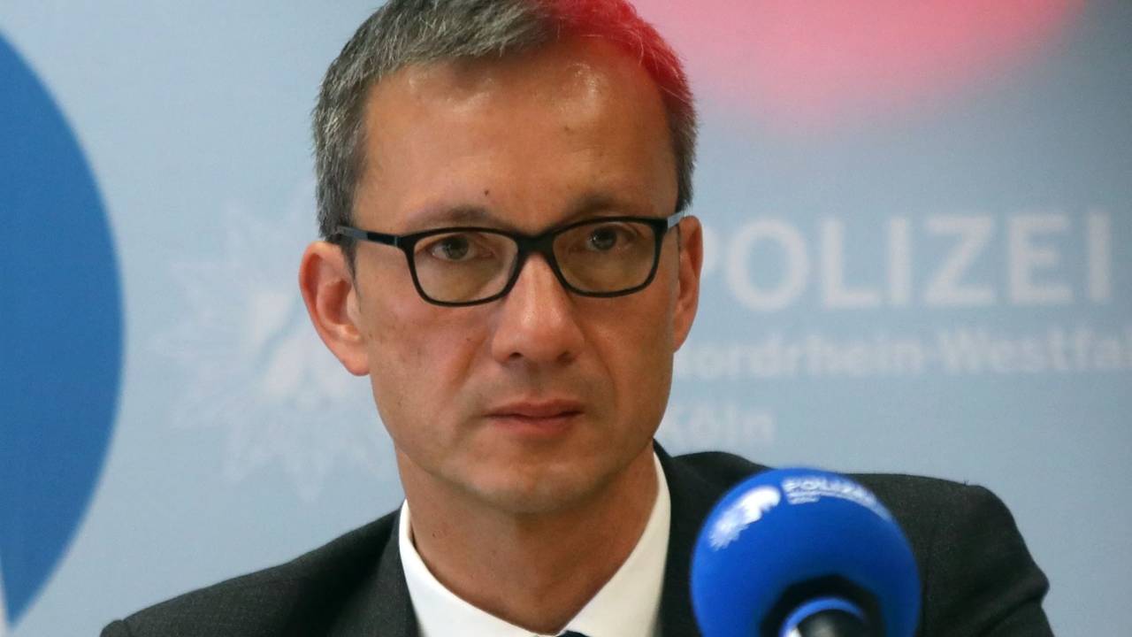 Der Kölner Polizeipräsident Falk Schnabel sitzt auf einem Podium vor einem Mikrofon.