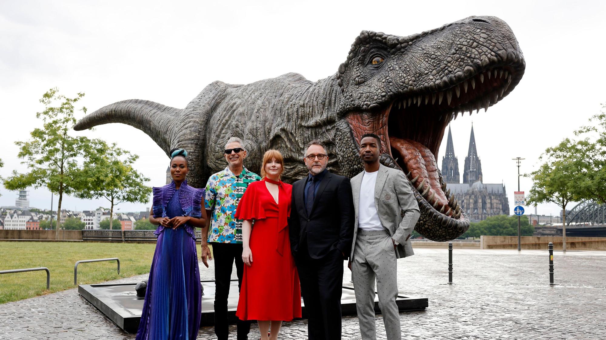 Die Schauspieler DeWanda Wise (v.l.), Jeff Goldblum, Bryce Dallas Howard, Regisseur Colin Trevorrow und Mamoudou Athie stehen vor einer T-Rex Figur.