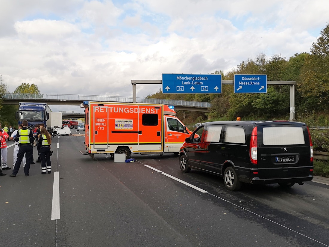 Polizisten und Rettungskräfte stehen neben einem Krankenwagen und einem Leichenwagen auf einer Fahrbahn der Autobahn A44.