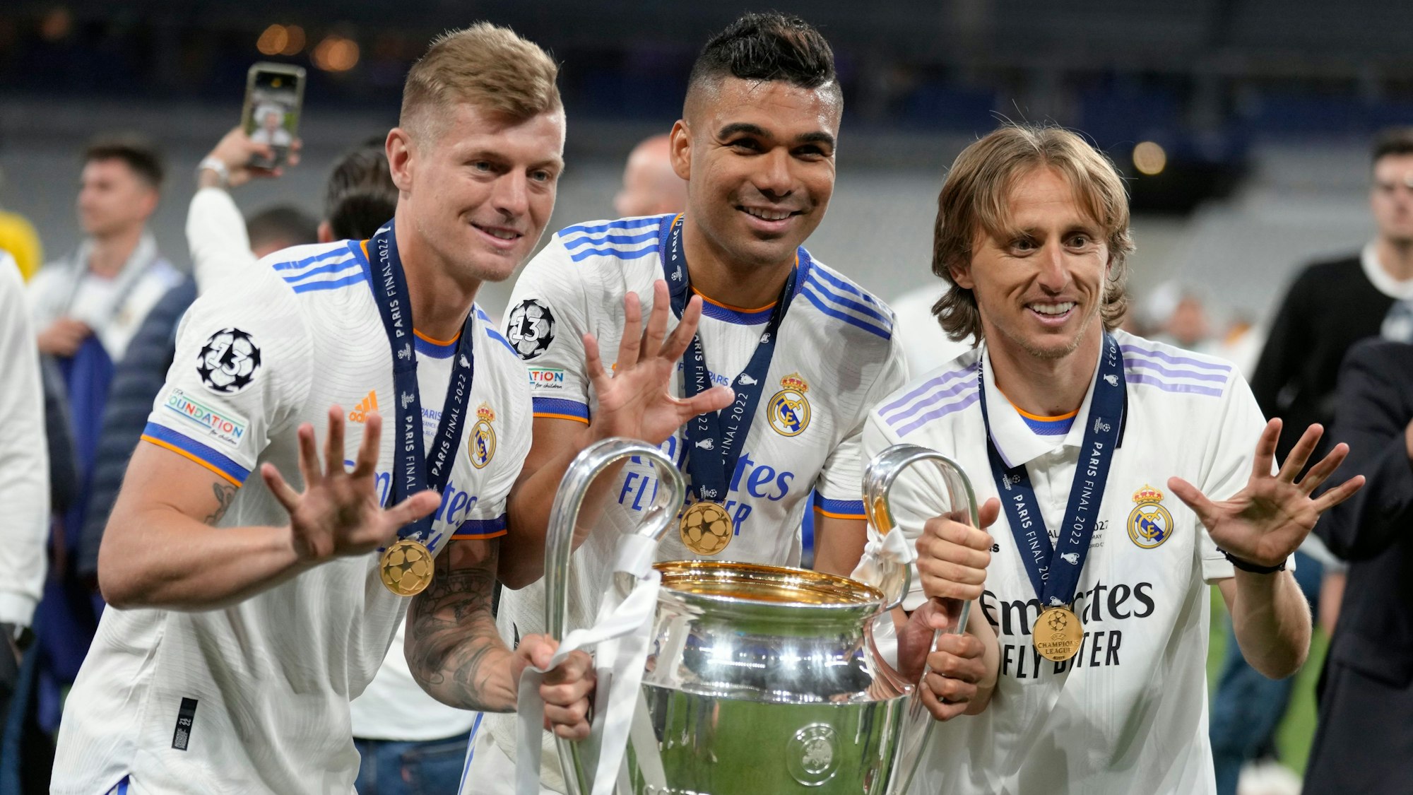 Toni Kroos (l.) posiert am 28. Mai 2022 mit Casemiro (Mitte) und Luka Modric mit der Champions-League-Trophäe.