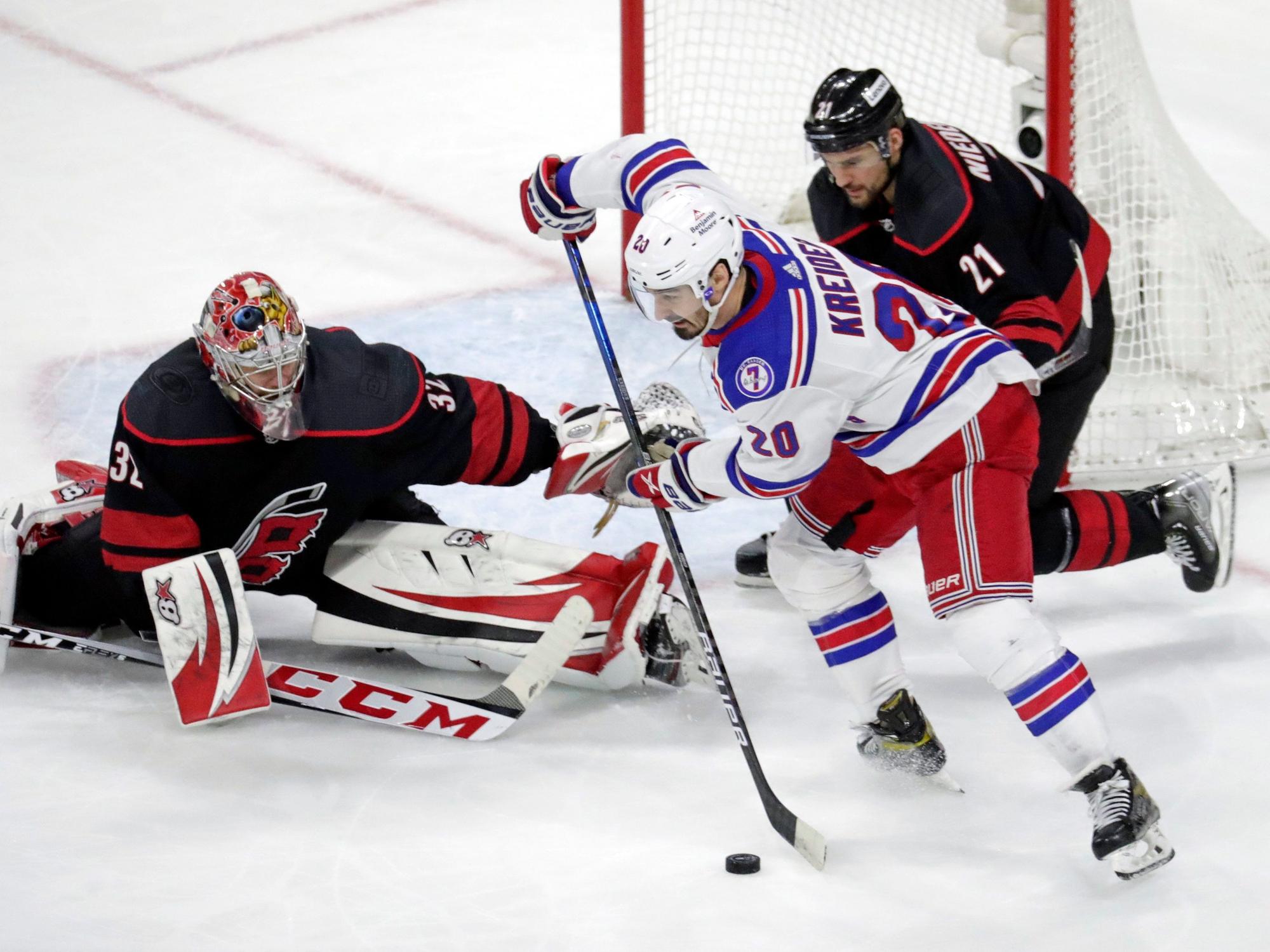 Chris Kreider (M, 20) von den New York Rangers in Aktion gegen Torwart Antti Raanta (32) und Nino Niederreiter (r, 21) von den Carolina Hurricanes.