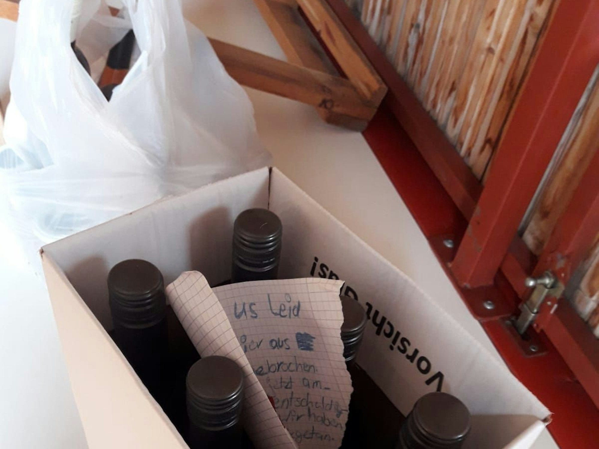 In einem Karton mit Flaschen steckt der Entschuldigungsbrief, daneben eine Plastiktüte mit Marmelade.