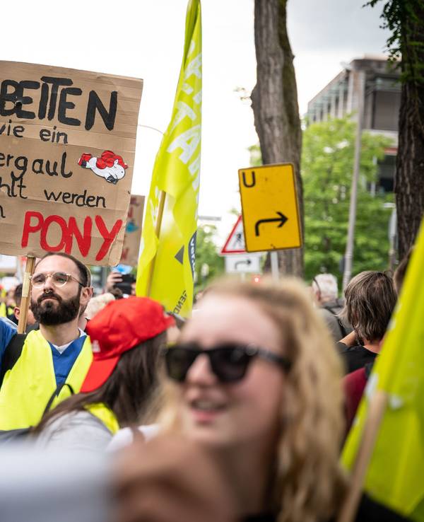 Mit einem Plakat "Arbeiten wie ein Ackergaul - bezahlt werden wie ein Pony" nehmen Pflegekräfte an einer Demonstration teil.