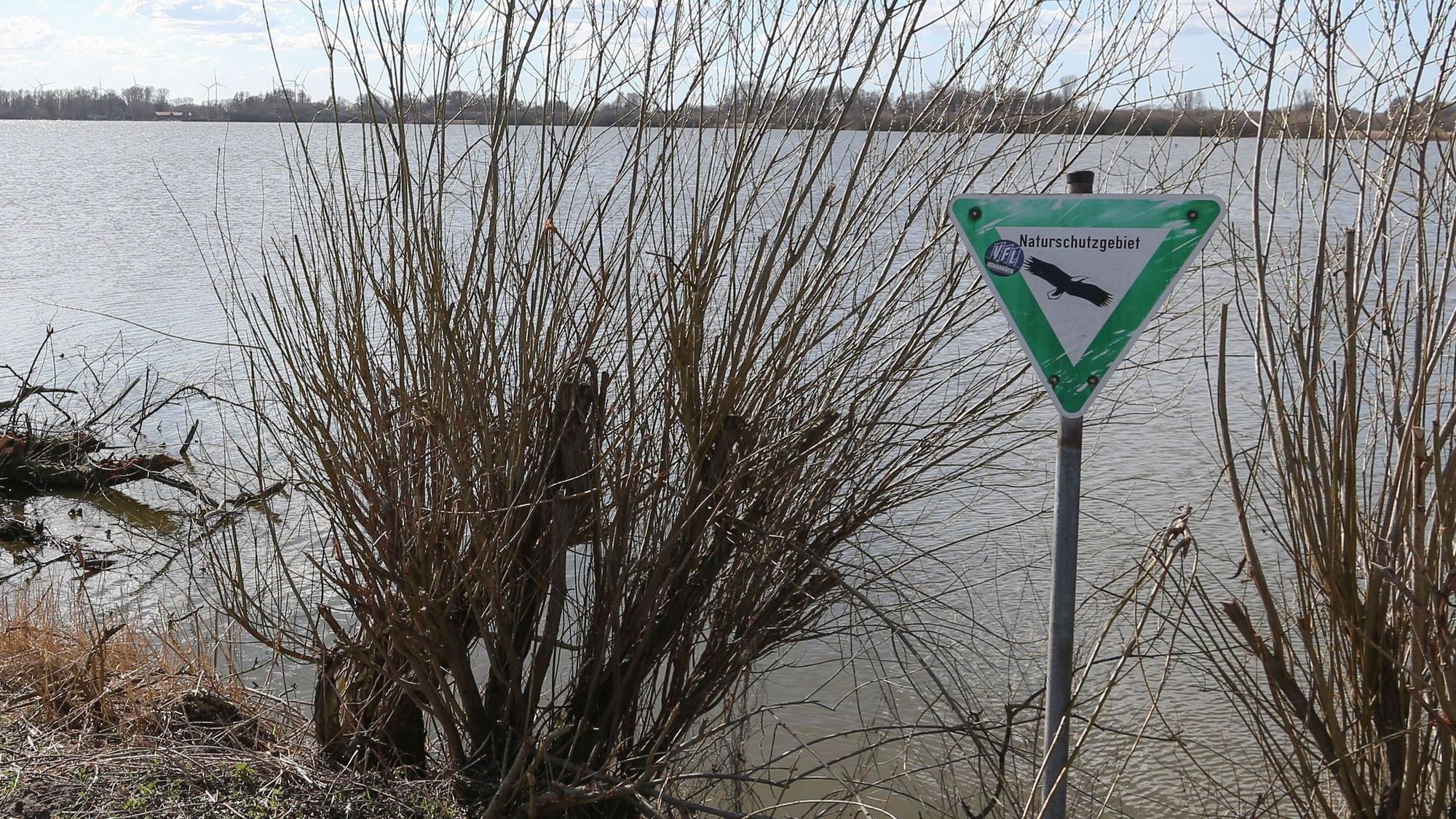 Ein Schild an einem See weist auf ein Naturschutzgebiet hin.