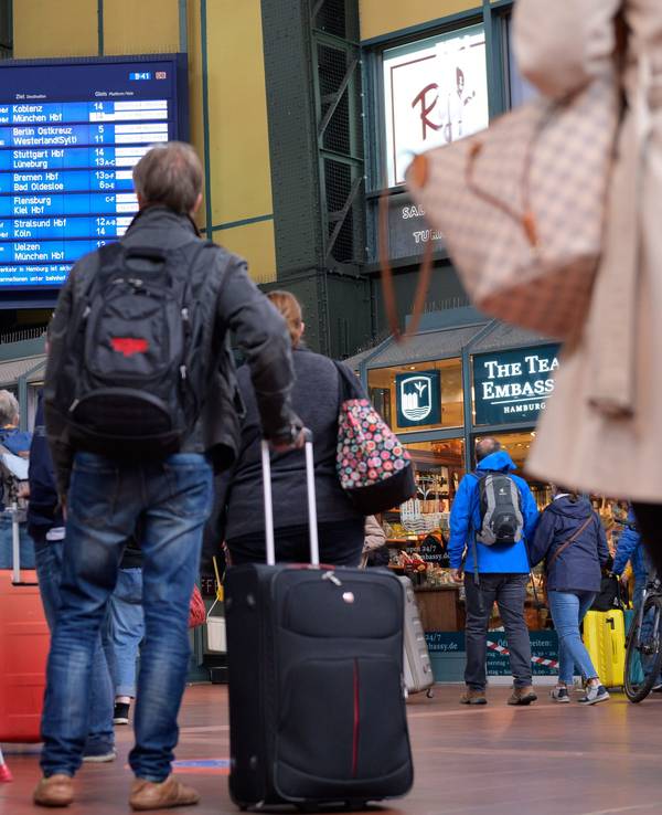 Zahlreiche Reisende vor einer Anzeigetafel mit An- und Abfahrtszeiten der Züge am Hamburger Hauptbahnhof.