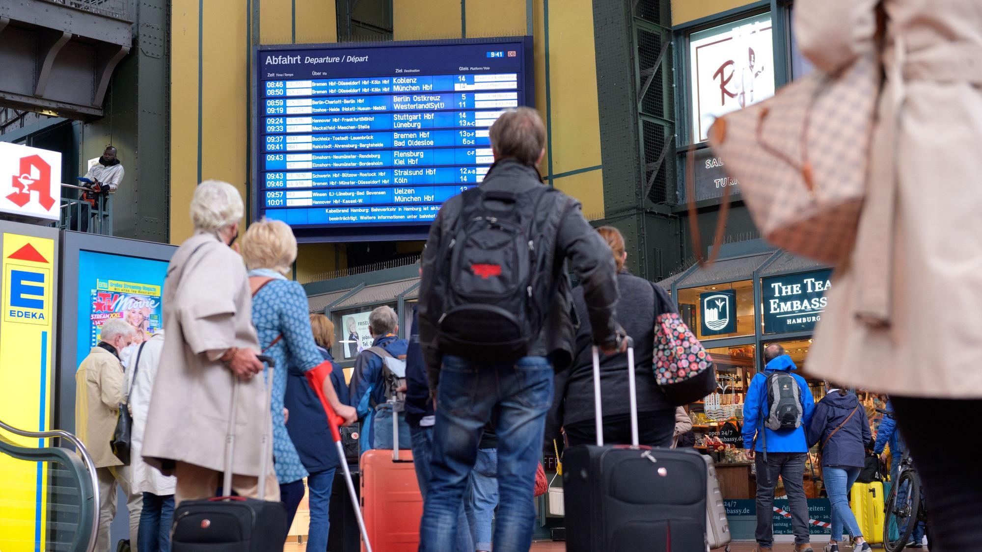 Zahlreiche Reisende vor einer Anzeigetafel mit An- und Abfahrtszeiten der Züge am Hamburger Hauptbahnhof.