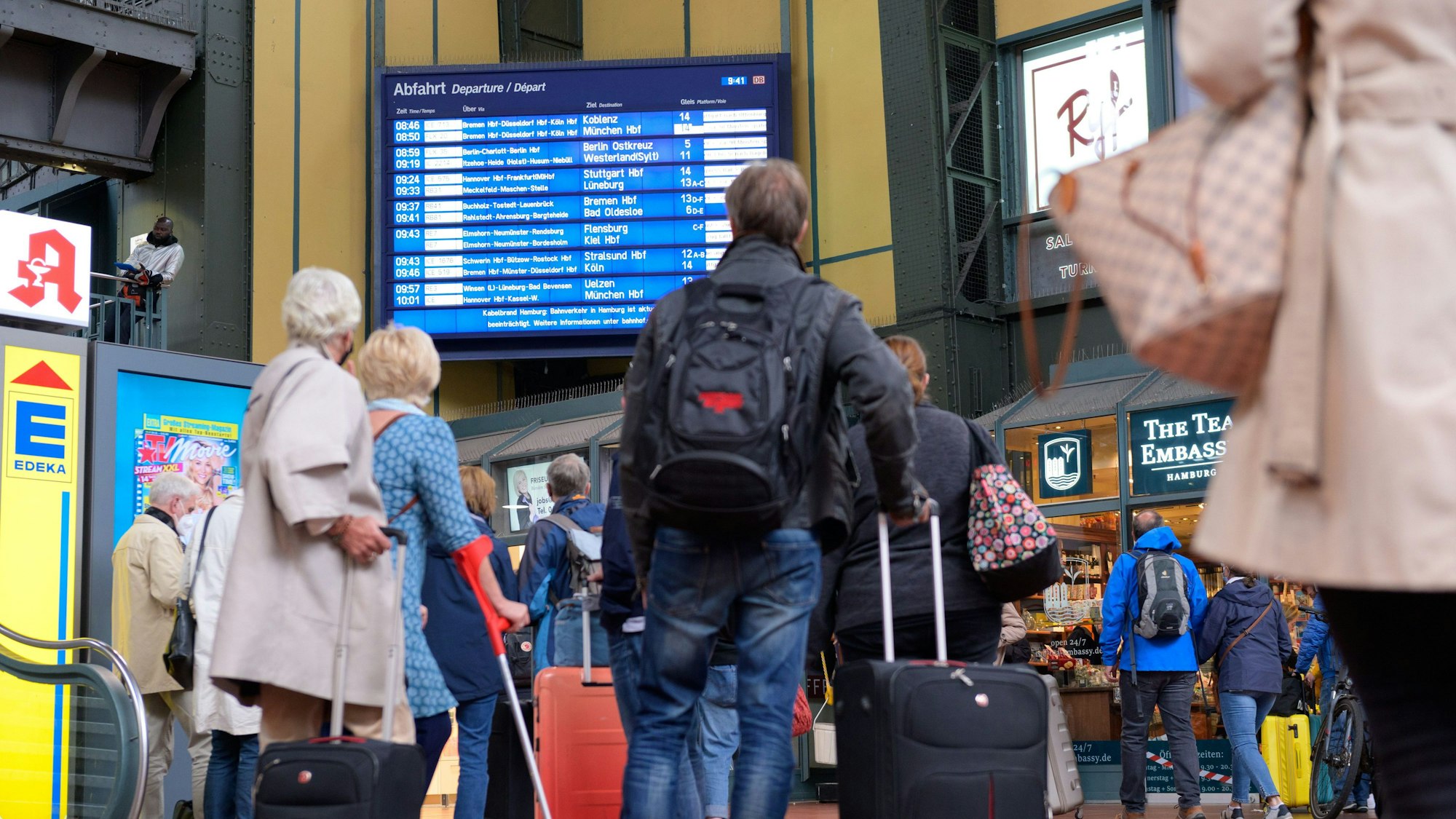 Zahlreiche Reisende vor einer Anzeigetafel mit An- und Abfahrtszeiten der Züge am Hamburger Hauptbahnhof.