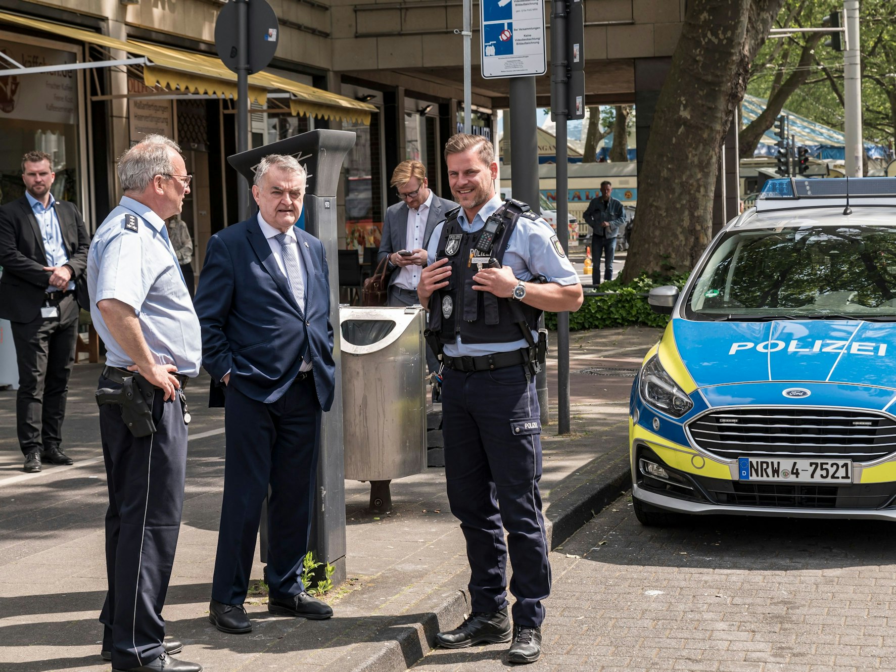 Innenminister Herbert Reul im Gespräch mit zwei Polizisten vor einem Streifenwagen am Neumarkt.