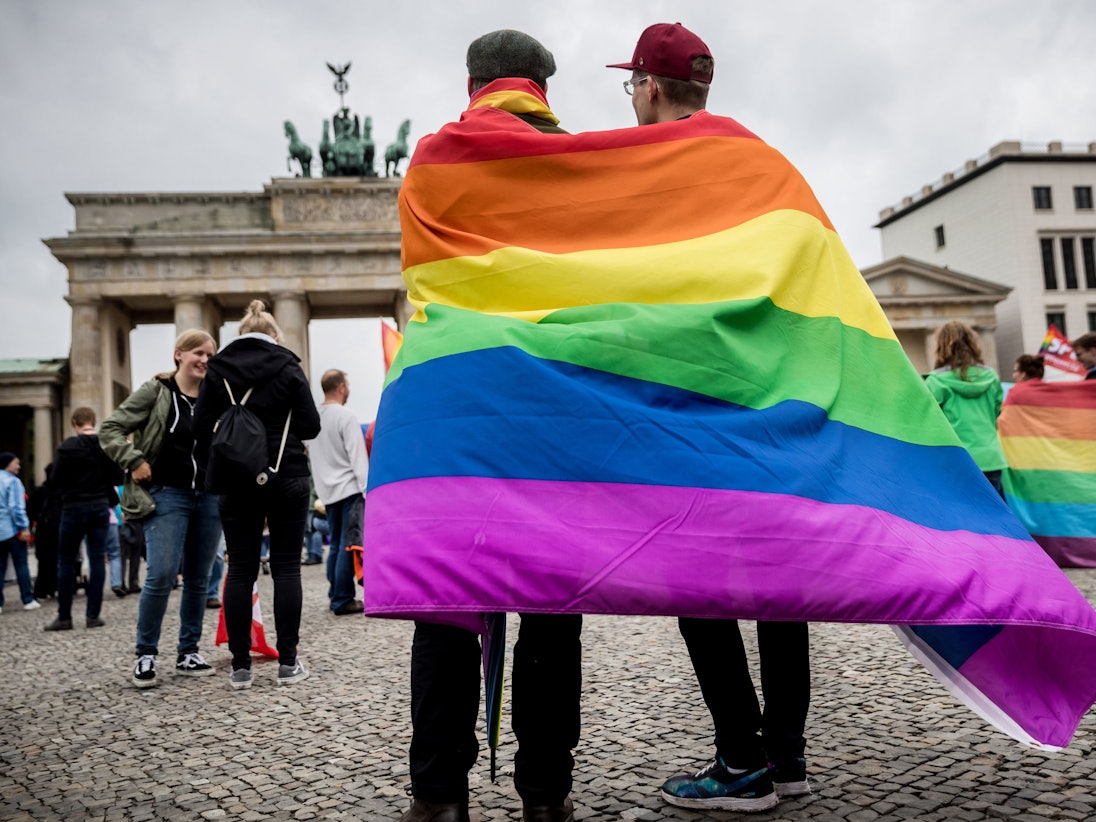 Marcel J. aus Dresden (l) und Henri V. aus Berlin stehen, gehüllt in eine Regenbogenflagge, am 30.06.2017 bei einer Veranstaltung der SPD zur Ehe für alle vor dem Brandenburger Tor in Berlin.