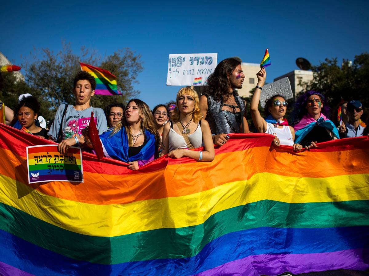 Menschen marschieren mit Regenbogenfahnen und Schildern während der jährlichen Gay-Pride-Parade durch die Straßen.