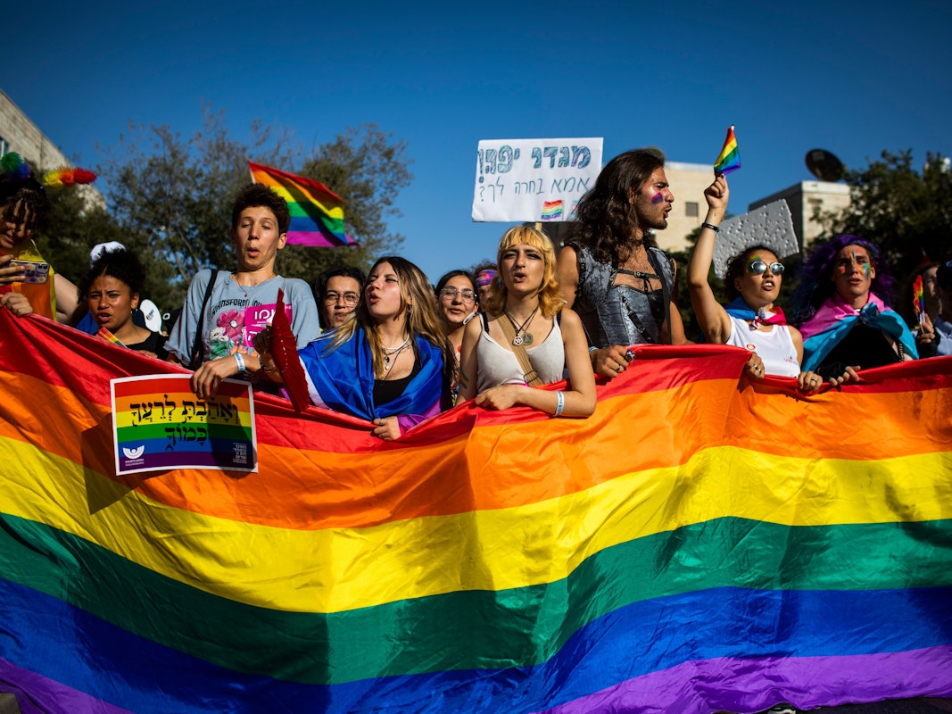 Menschen marschieren mit Regenbogenfahnen und Schildern während der jährlichen Gay-Pride-Parade durch die Straßen.