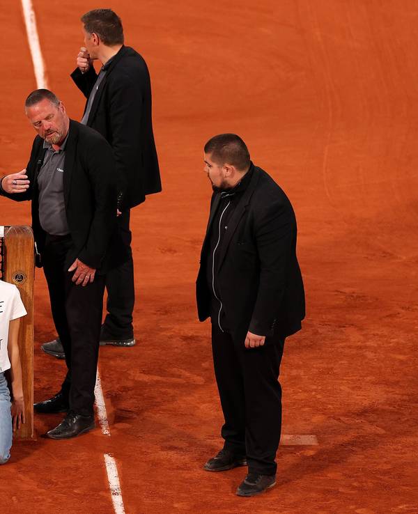 Sicherheitsmitarbeiter stehen um die Aktivistin am Netz bei den French Open.