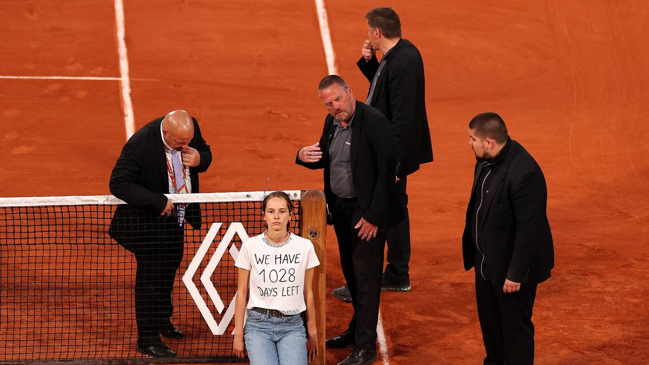 Sicherheitsmitarbeiter stehen um die Aktivistin am Netz bei den French Open.