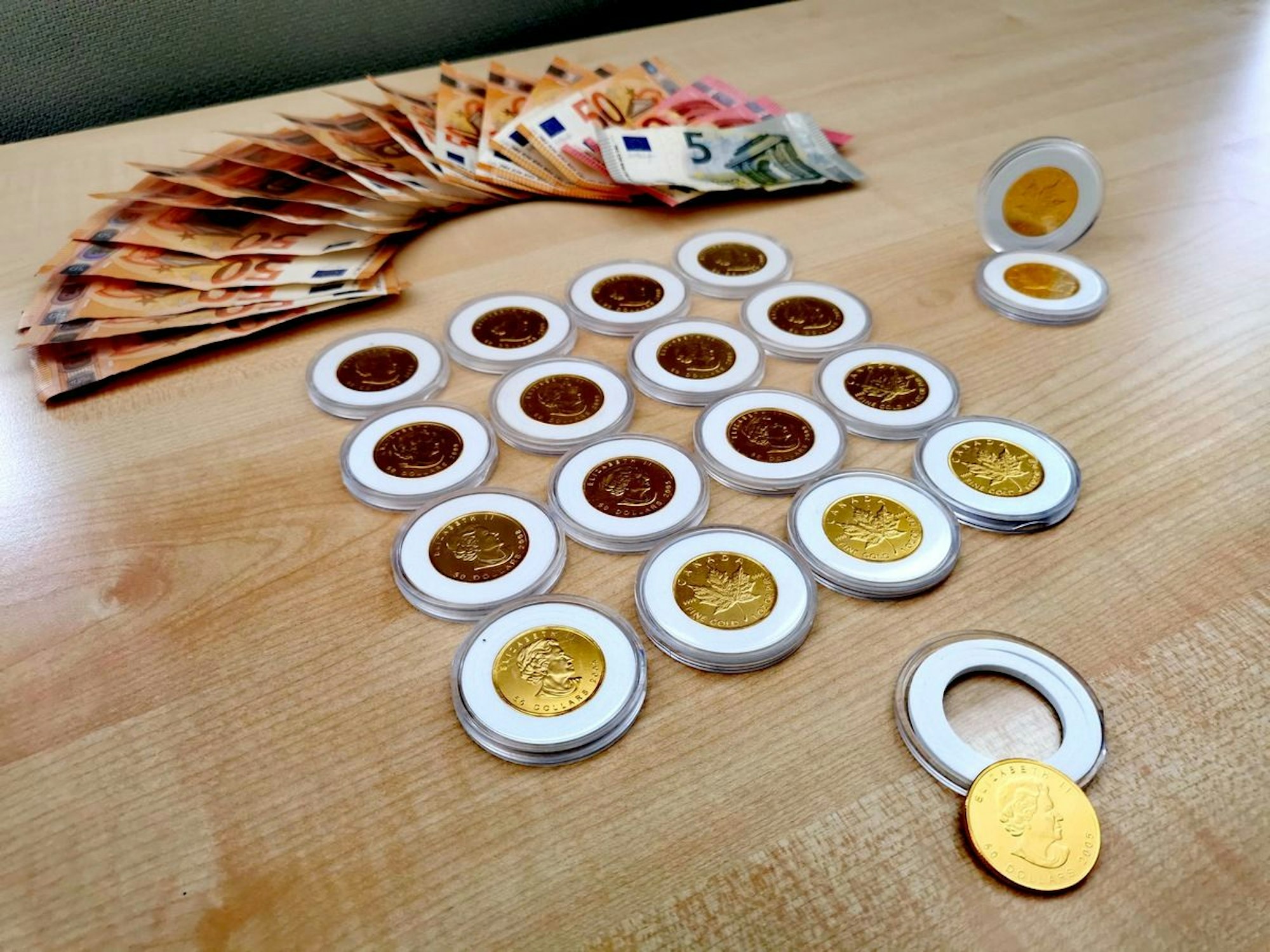 Gefälschte Goldmünzen und mehrere 100 Euro Bargeld liegen auf einem Tisch.