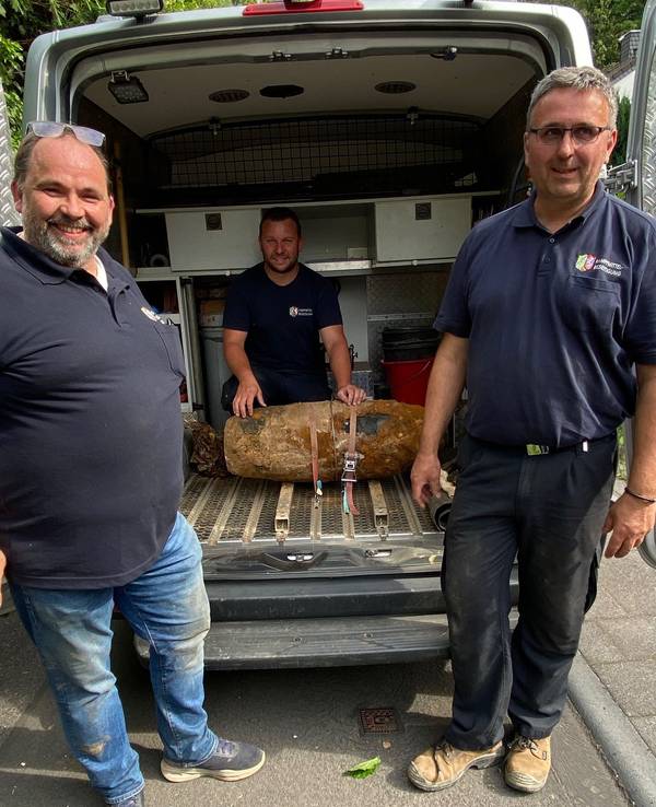 Drei Männer stehen vor einer entschärften Bombe.