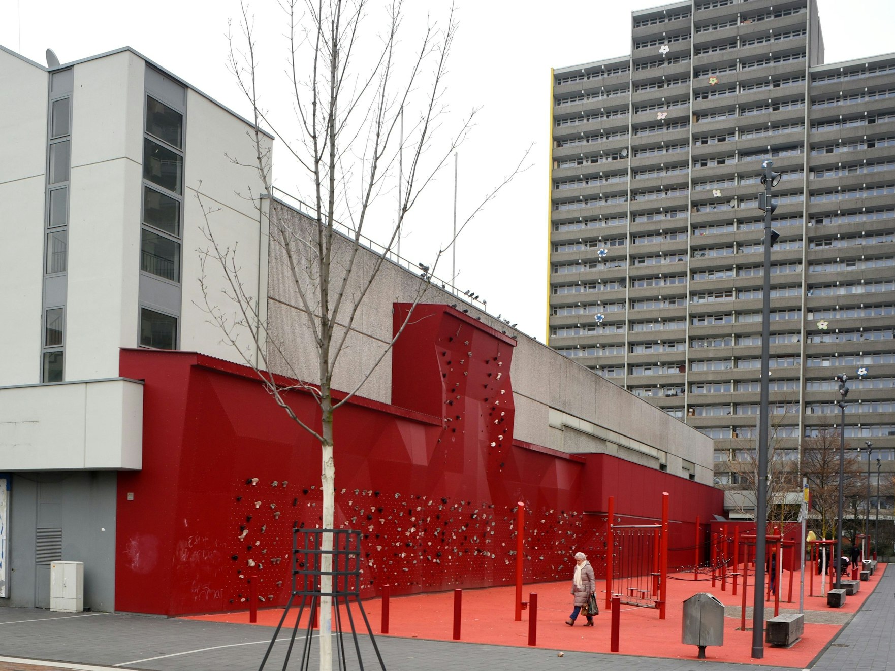 Ein rot angestrichener Sportparcours mit Boulderwand an einem Gebäude.