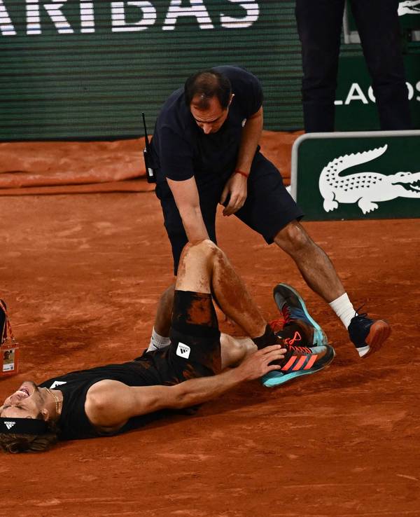 Alexander Zverev liegt schreiend am Boden, während ihn ein Arzt behandelt. Gegenspieler Rafael Nadal leidet daneben mit.