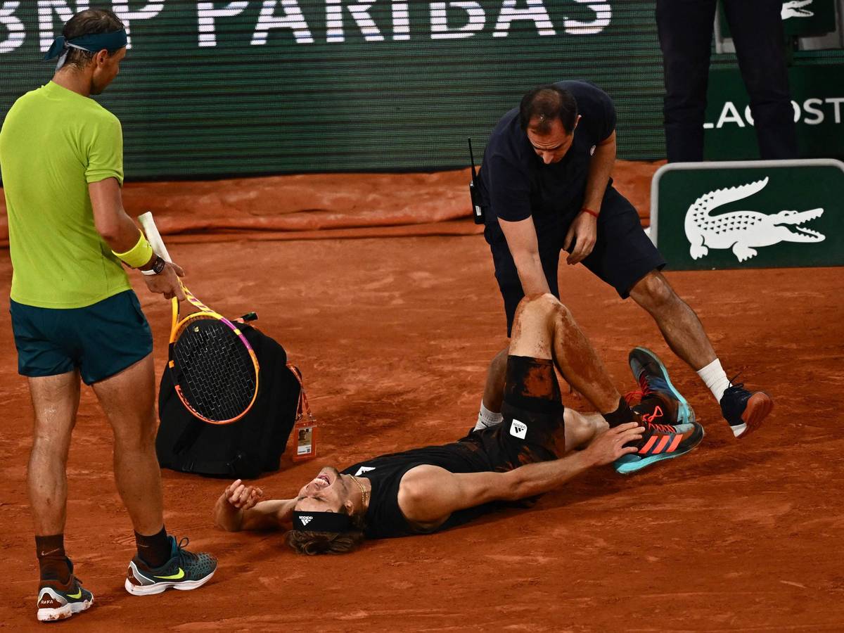 Alexander Zverev liegt schreiend am Boden, während ihn ein Arzt behandelt. Gegenspieler Rafael Nadal leidet daneben mit.
