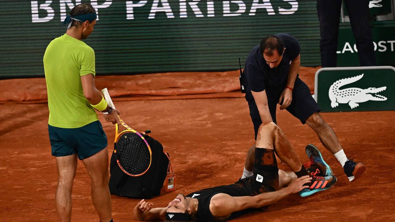 Alexander Zverev liegt schreiend am Boden, während ihn ein Arzt behandelt. Gegenspieler Rafael Nadal leidet daneben mit.