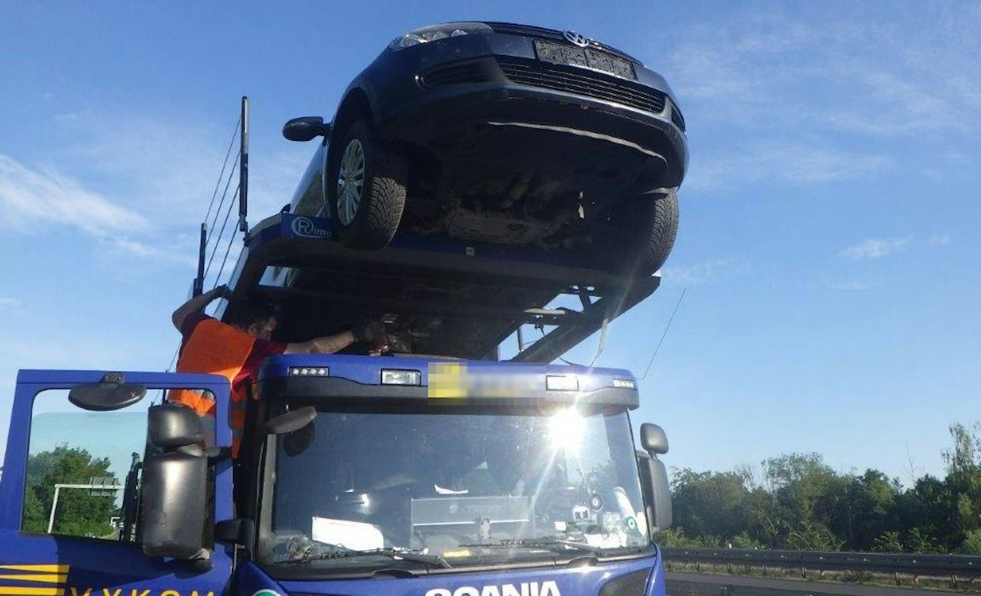 Ein Auto ragt weiter über die Fahrerkabine eines Transporters hinaus.