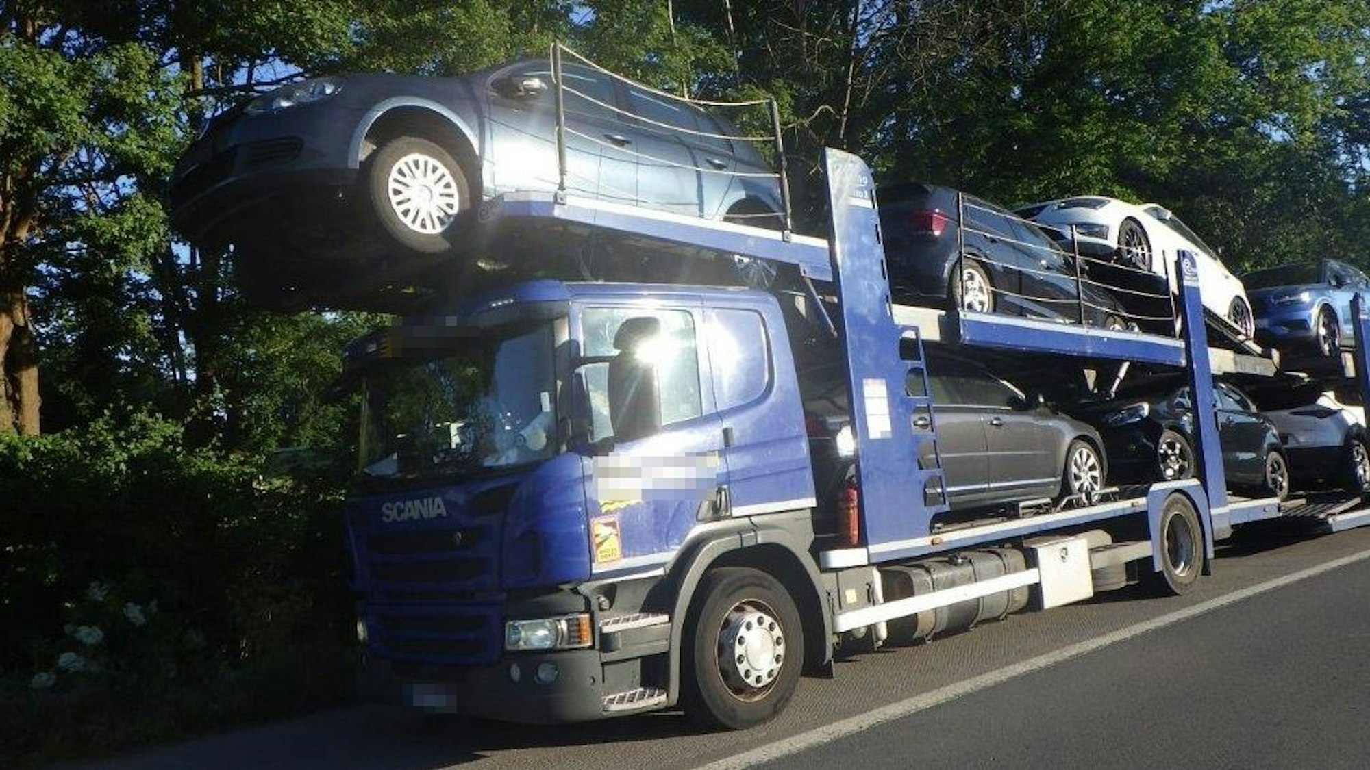 Ein Auto ragt mit seinen Vorderreifen über die Fahrerkabine des Autotransporters hinaus.