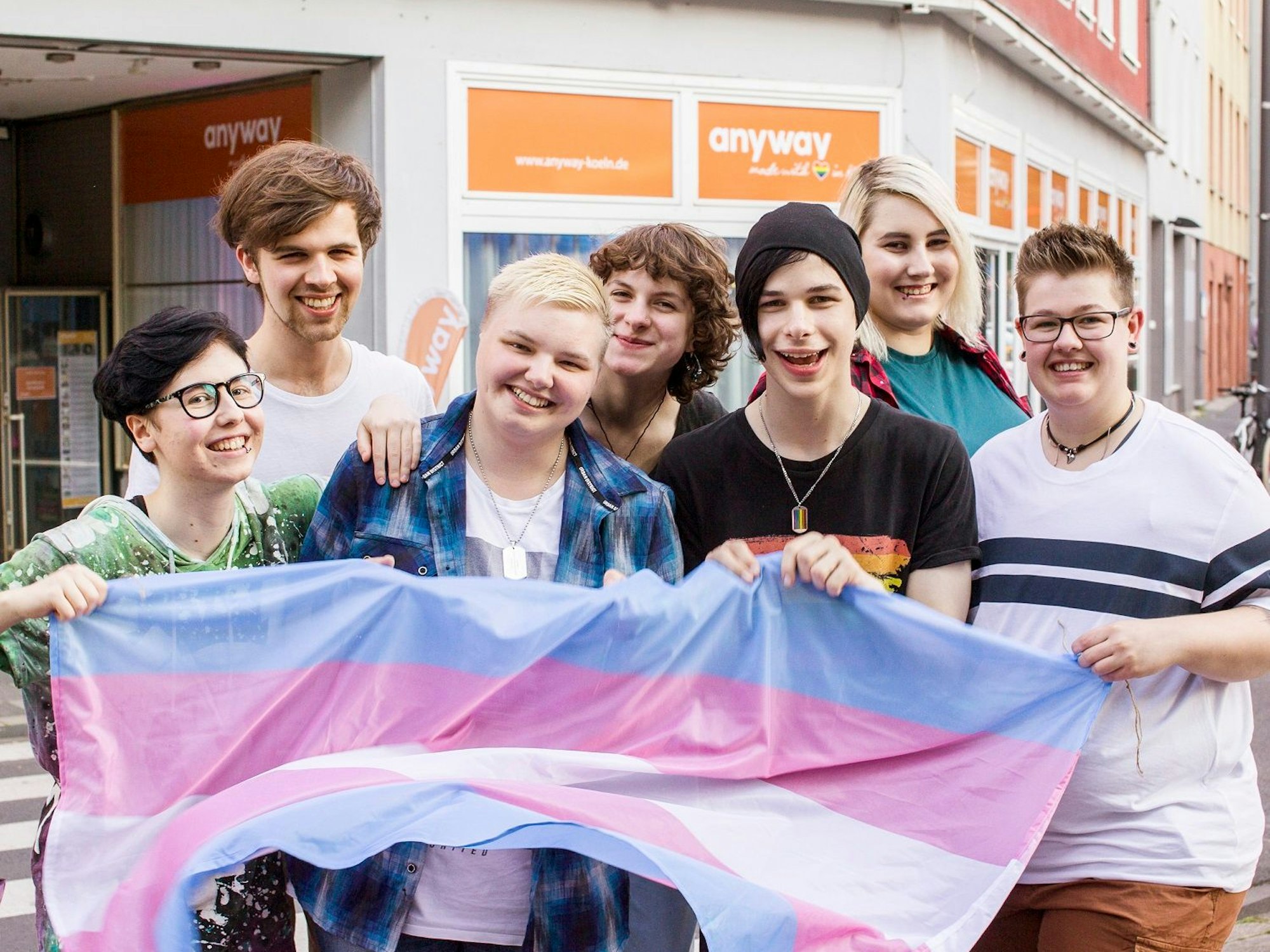 Jugendliche stehen mit Regenbogen-Fahne auf einer Straße in Köln.