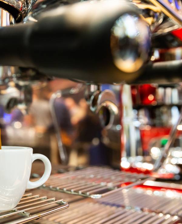 Ein Espresso läuft aus einer Espressomaschine in eine Tasse.