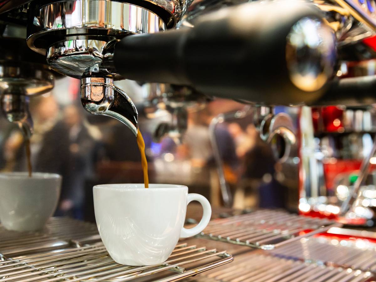 Ein Espresso läuft aus einer Espressomaschine in eine Tasse.