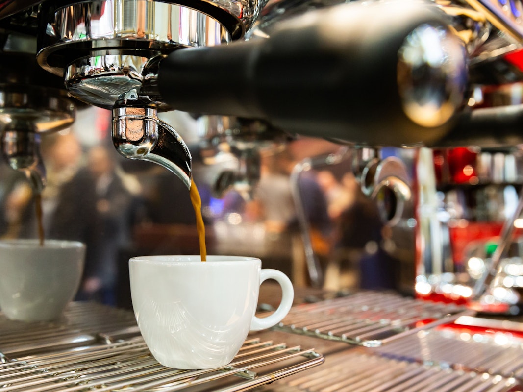 Ein Espresso läuft aus einer Espressomaschine in eine Tasse.