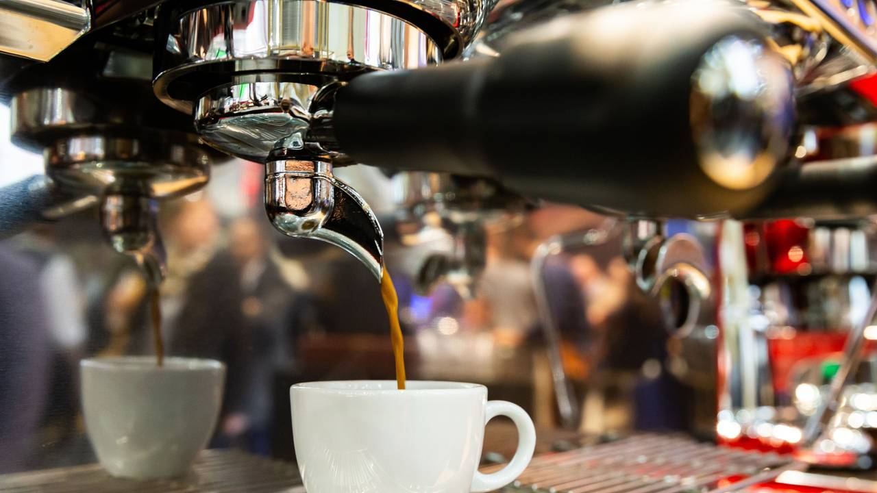Ein Espresso läuft aus einer Espressomaschine in eine Tasse.
