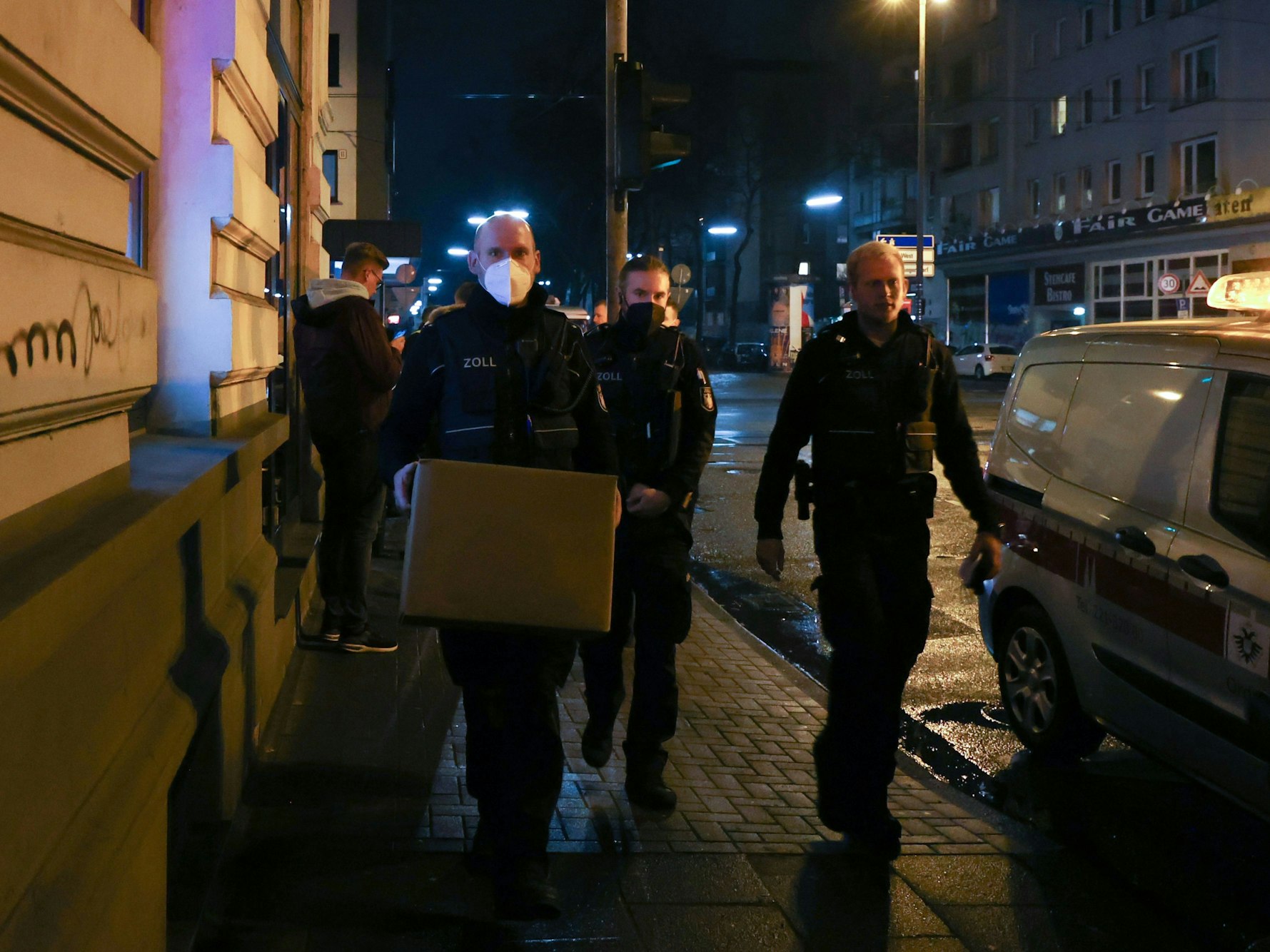 Zoll-Beamte gehen mit sichergestellten Kisten durch die Straße.