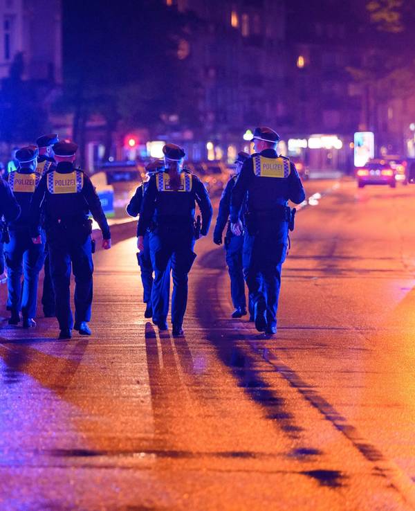 Polizeikräfte laufen zu ihren Streifenwagen.