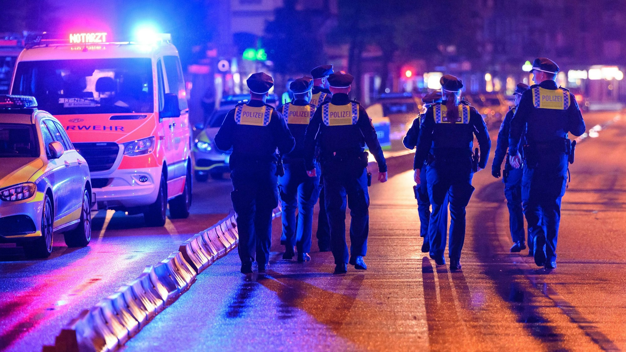 Polizisten laufen nach dem Einsatz zu ihren Streifenwagen.