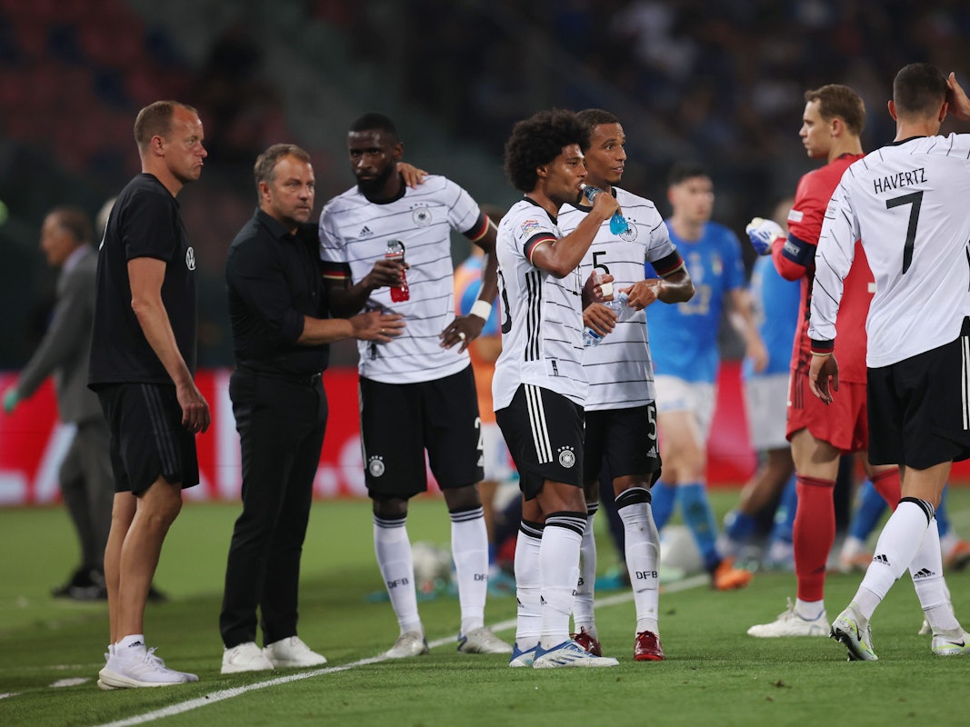 Die Nationalspieler stehen bei Trainer Hansi Flick und trinken etwas.