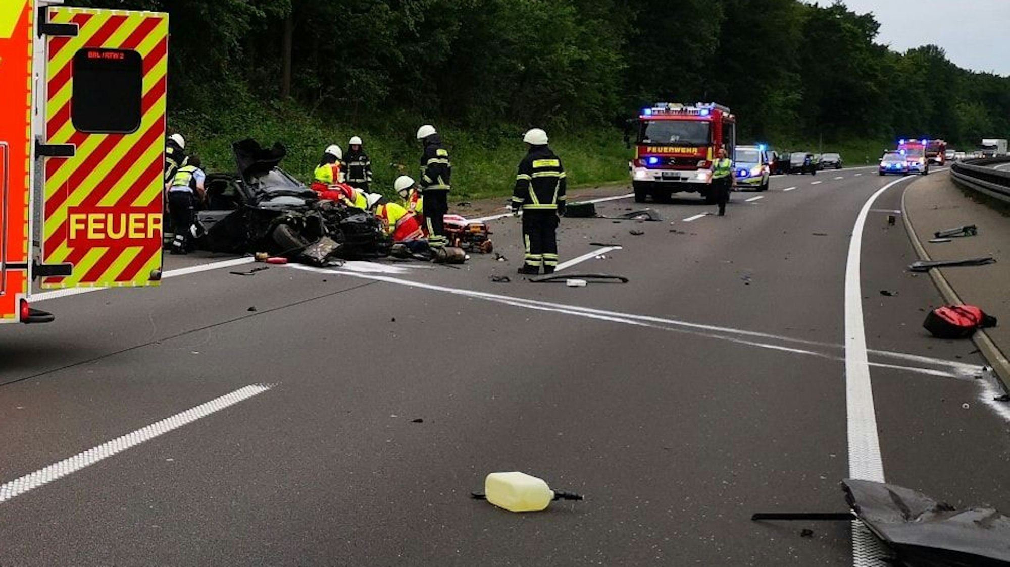 Auf der Autobahn liegen überall Trümmerteile, Kräfte von Rettungsdienst und Feuerwehr kümmern sich um den Fahrer eines völlig zerfetzten Mercedes.