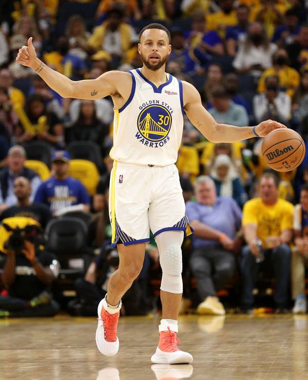 Steph Curry dribbelt mit der einen Hand, während er mit der anderen einen Daumen nach oben zeigt.