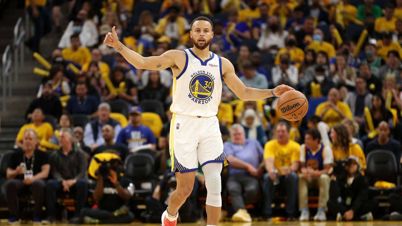 Steph Curry dribbelt mit der einen Hand, während er mit der anderen einen Daumen nach oben zeigt.