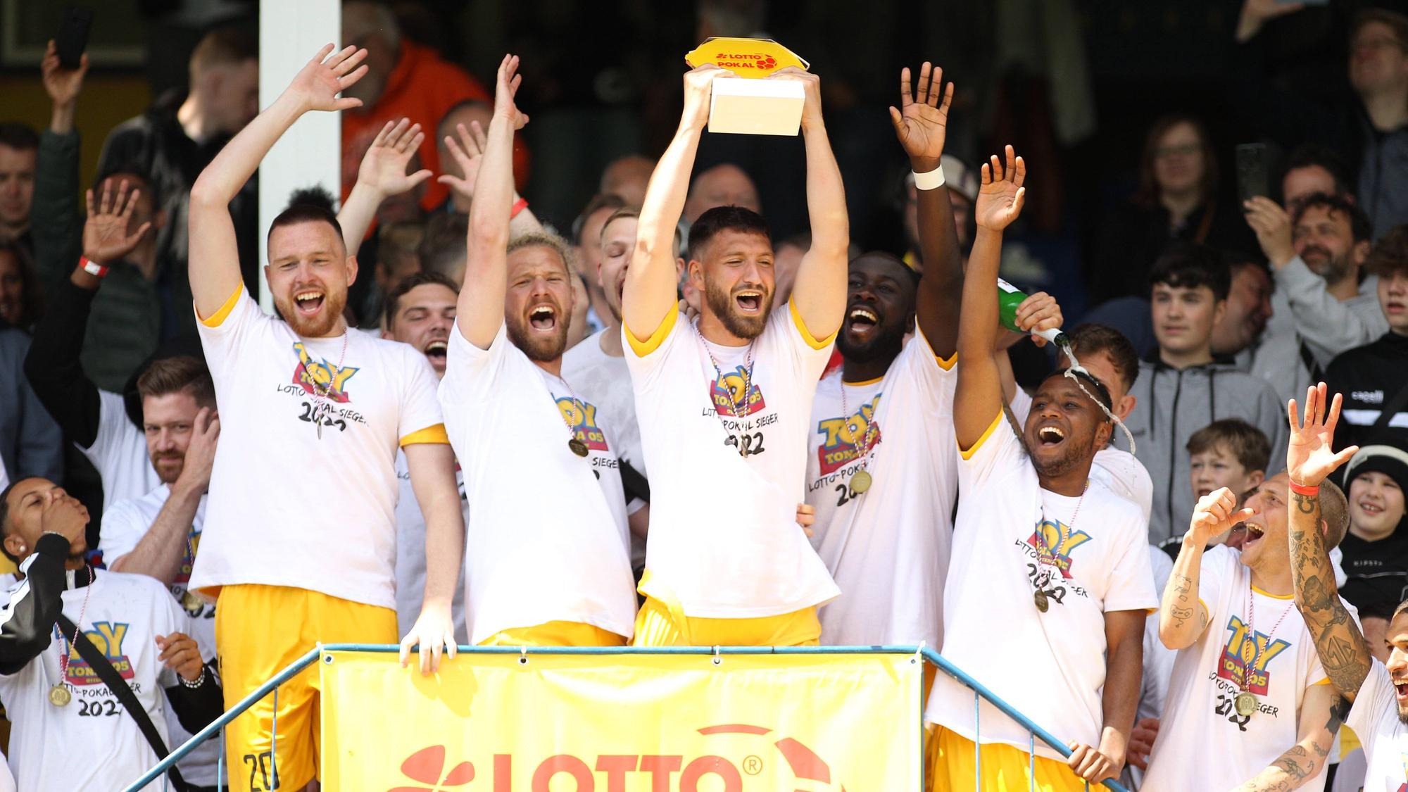 Die Spieler des FC Teutonia Ottensen um Marcel Andrijanic mit Pokal in den Händen bejubeln den Sieg im Hamburger Verbandspokal.