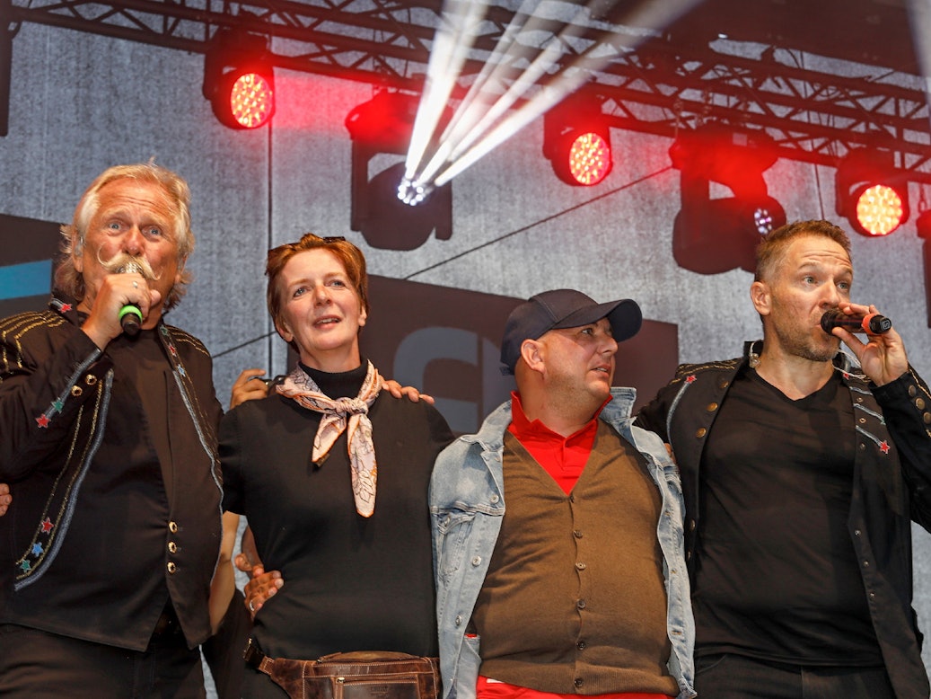Henning Krautmacher und Patrick Lück von den Höhnern stehen mit Anke und Michael aus Duisburg auf der Bühne.