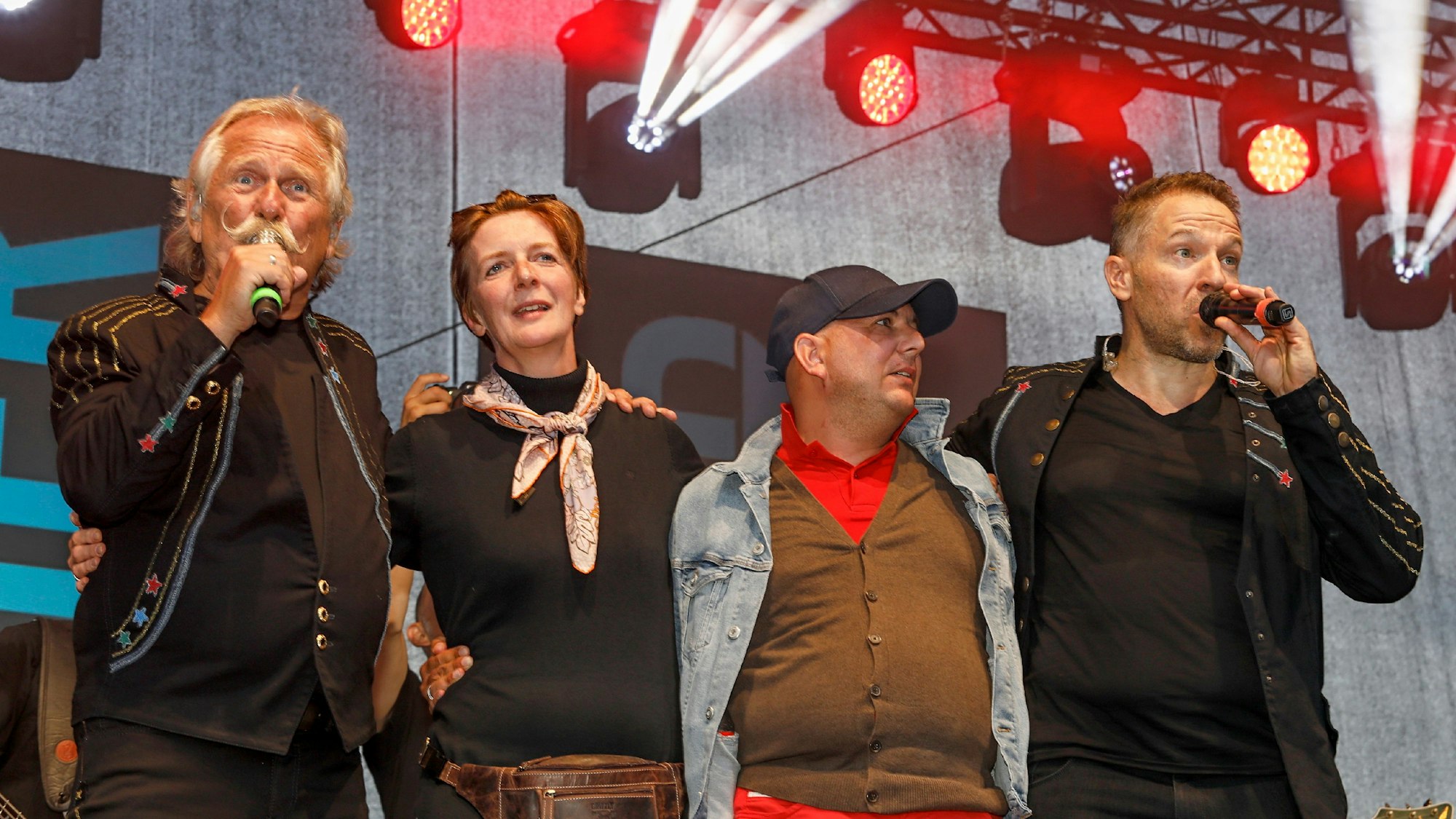 Henning Krautmacher und Patrick Lück von den Höhnern stehen mit Anke und Michael aus Duisburg auf der Bühne.