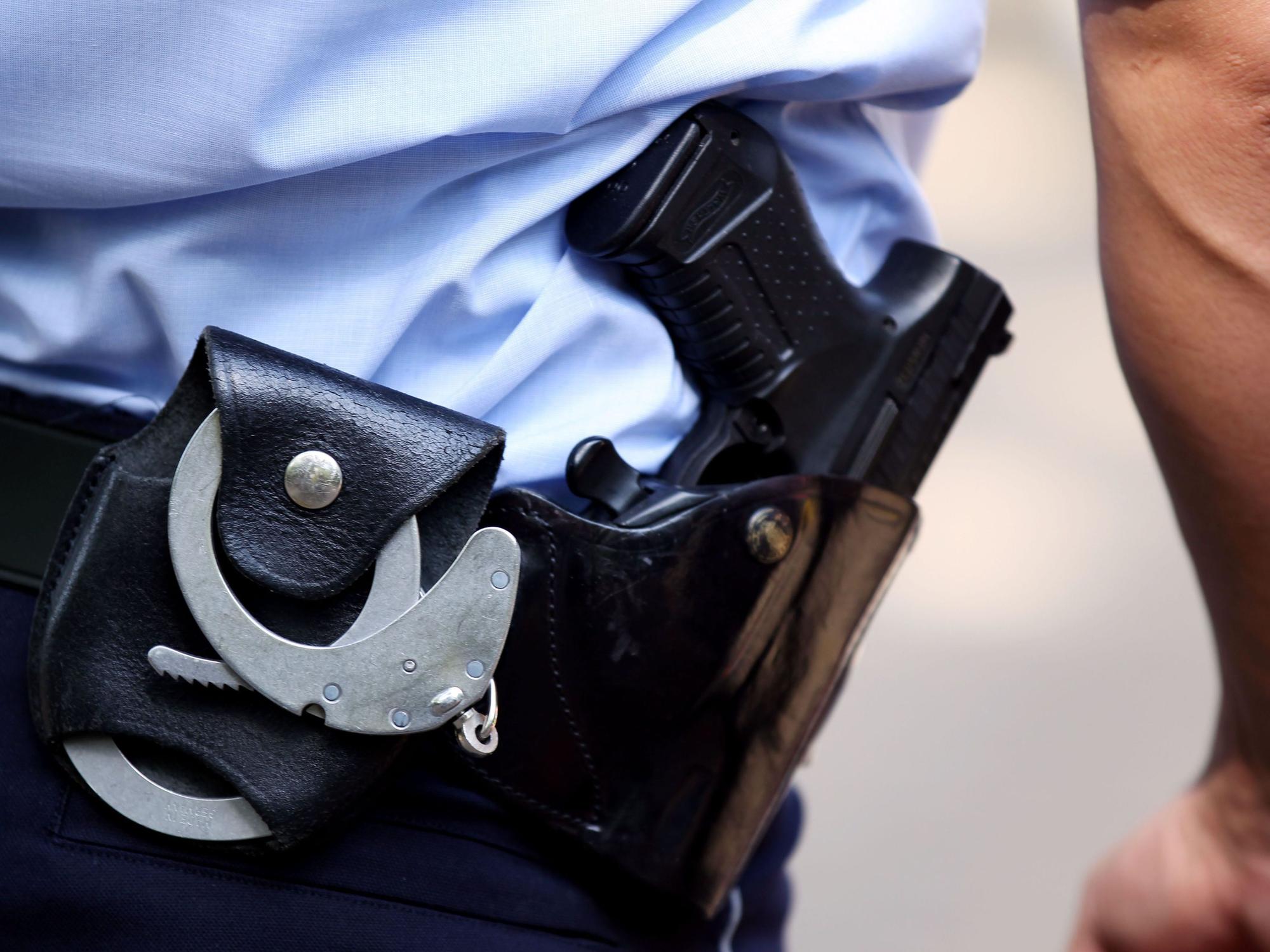 Ein Polizist mit Handschellen und Pistole am Gürtel.