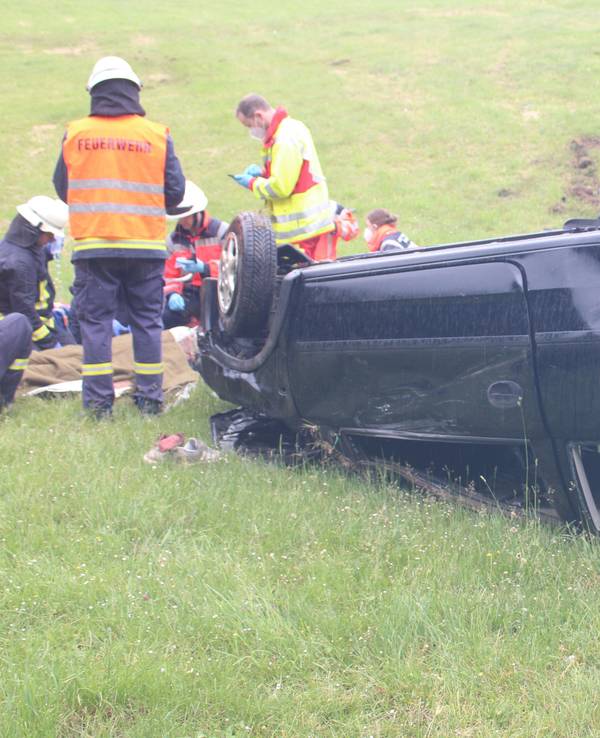 Einsatzkräfte kümmern sich um den Fahrer, der vor seinem Auto liegt.