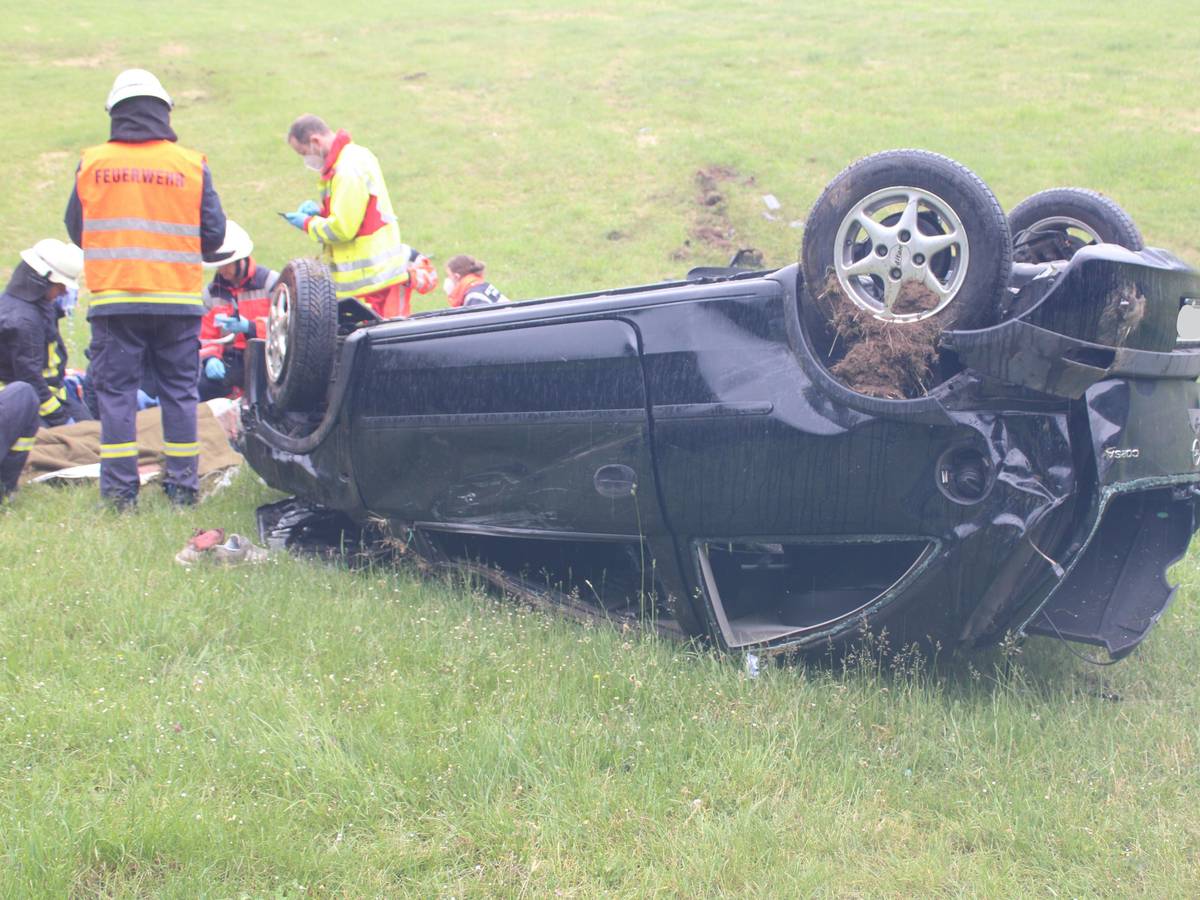 Einsatzkräfte kümmern sich um den Fahrer, der vor seinem Auto liegt.