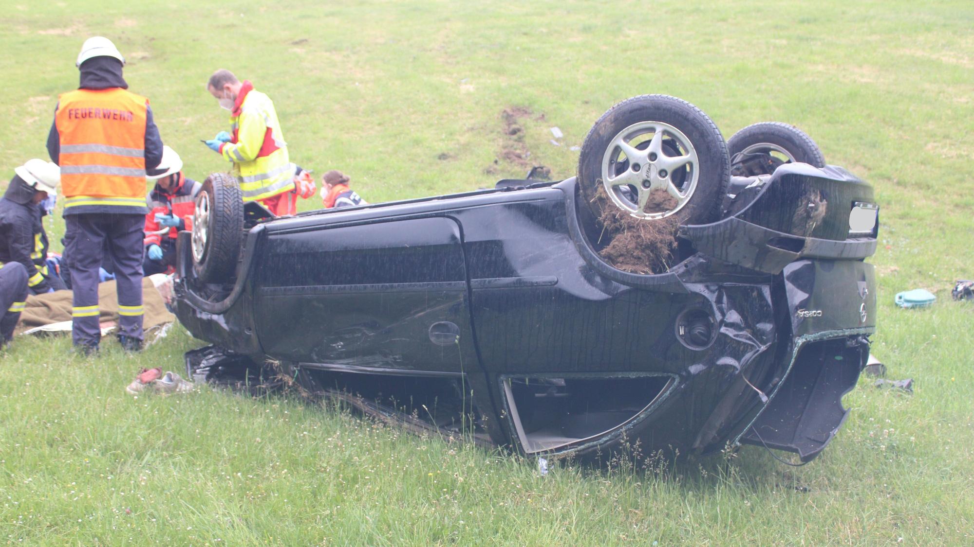 Einsatzkräfte kümmern sich um den Fahrer, der vor seinem Auto liegt.