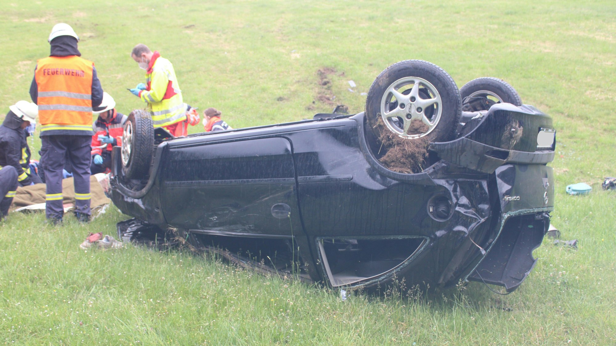Einsatzkräfte kümmern sich um den Fahrer, der vor seinem Auto liegt.